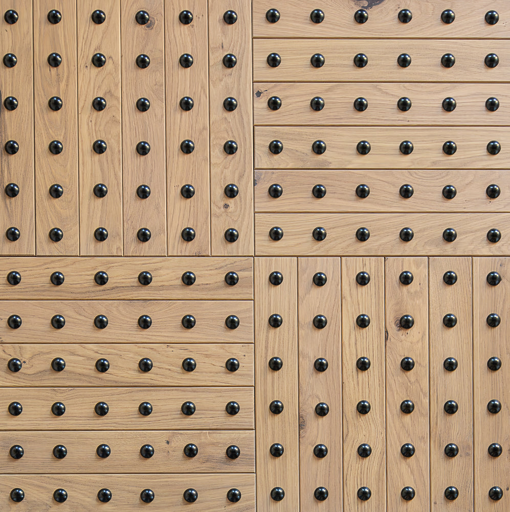 Wooden panel with a herringbone pattern and brass studs