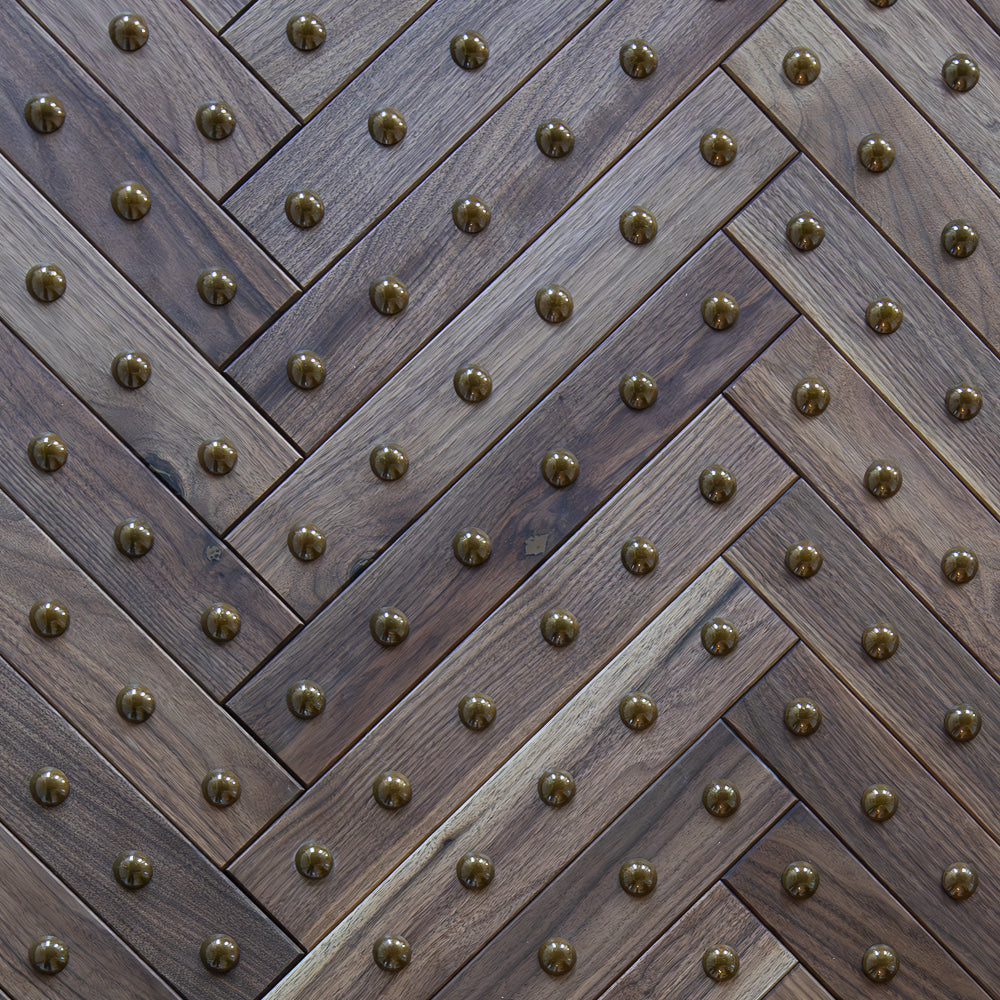 Wooden panel with a herringbone pattern and brass studs