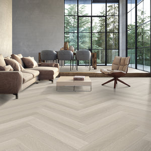 Light toned oak grain vinyl floors in herringbone configuration in a contemporary living room with floor to ceiling windows.