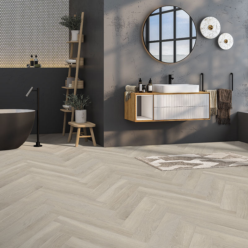 Light wood herringbone patterned flooring with subtle grain texture in soft beige and grey tones.