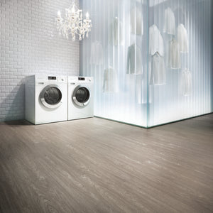 Modern laundry room with washing machines and a chandelier, with light brown heavily grained floor